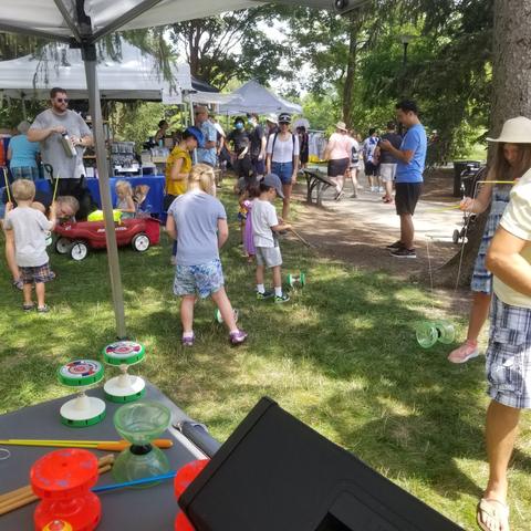 Kids and families spinning Chinese yo-yos together at an outdoor booth