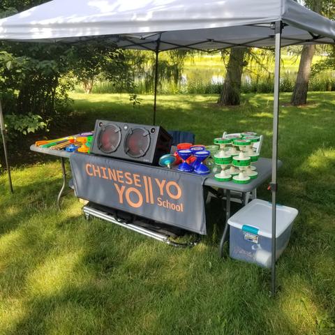 Chinese Yo-yo School booth tent with tables of colorful yo-yos at a park event