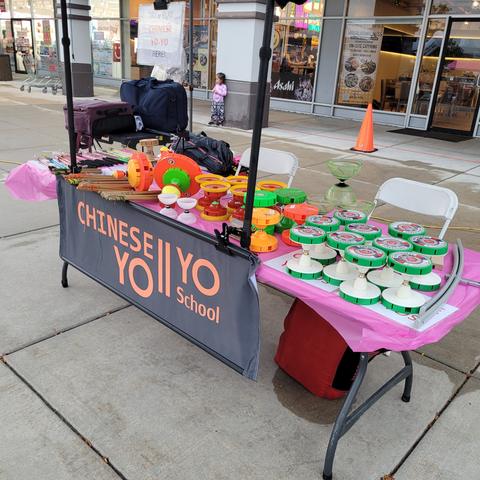 Booth table with pink covering stocked with colorful yo-yos outside shops
